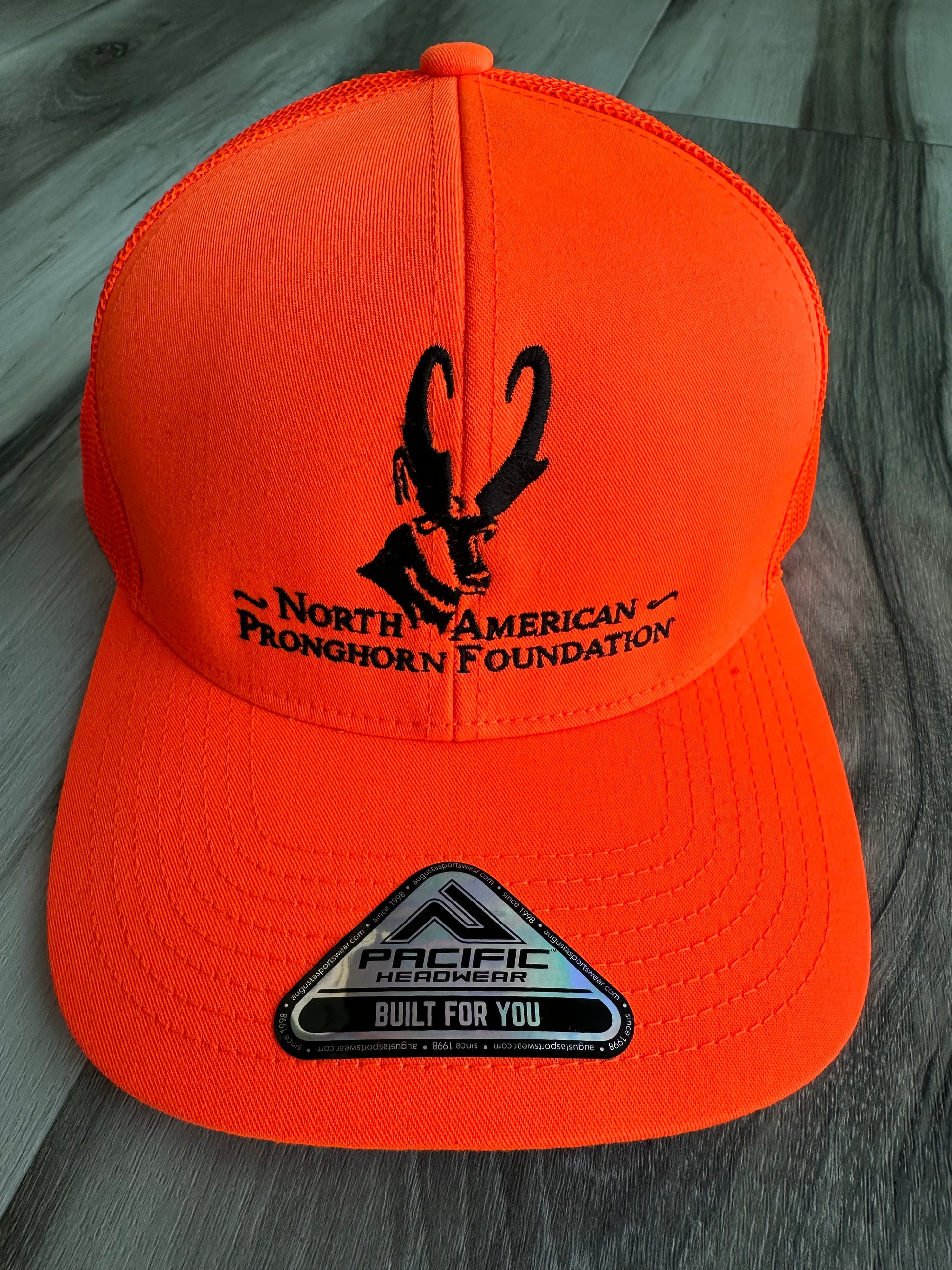 Orange cap with black logo and text on a wooden surface